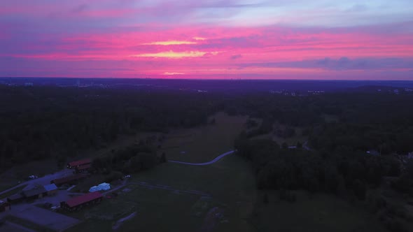 Aerial drone view backwards, above the countryside, purple sky, at a colorful sunset or dusk, at Alb