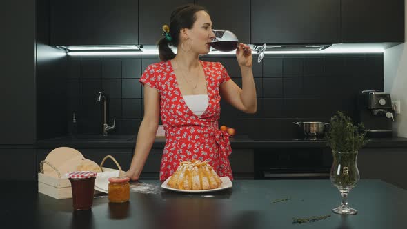 Woman prepared homemade pie and drinking red wine in modern professional kitchen. Food concept