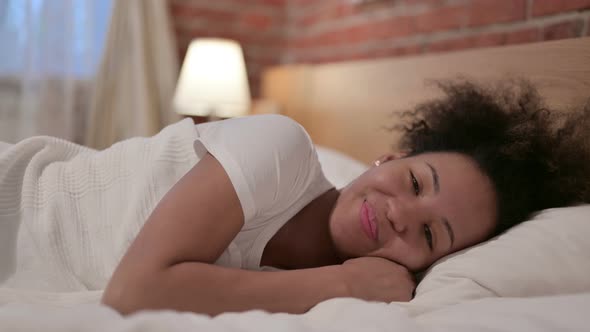 Happy African Woman Laying in Bed Smiling