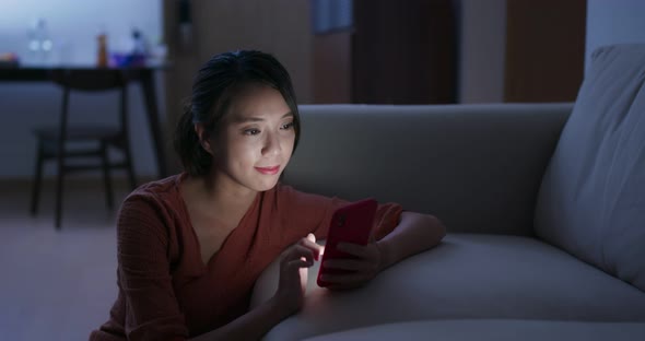 Woman use of mobile phone at home in the evening