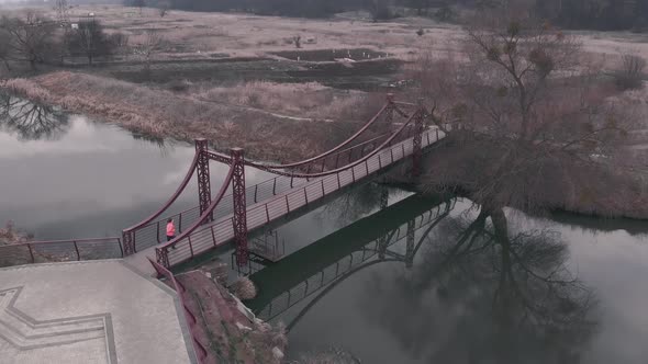 Woman athlete runs on pedestrian bridge across river. Running concept