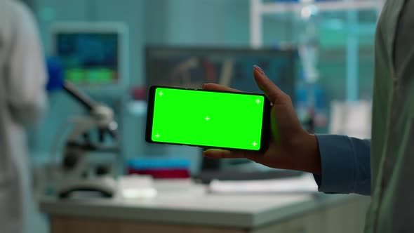 Close Up of Scientist Holding Horizontal Phone with Green Mockup alt