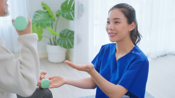 Asian older aged man doing physiotherapist with support from nurse at nursing home.