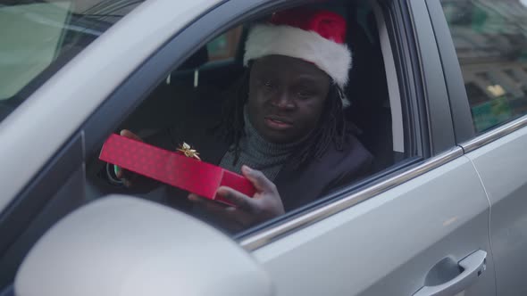 Handsome African American Man Giving a Christmas Gift Through the Window of His Car