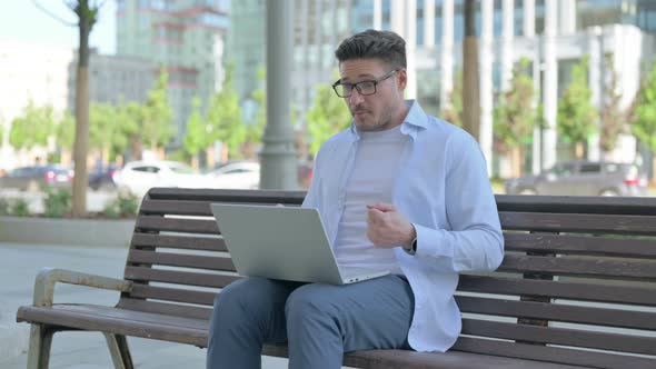 Man Talking on Video Call While Sitting Outdoor on Bench