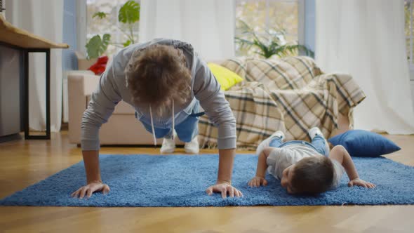 Father and Son Doing Sports on Blue Carpet in Living Room at Home