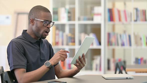 Failure Young African Man with Loss on Tablet in Library