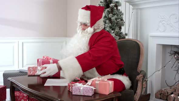 Santa Claus Preparing Presents for Children and Checking the Gift List