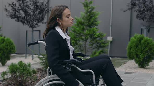 Crop View of Female Beautiful Person in Suit Pushing Herself on Wheel Chair at Street