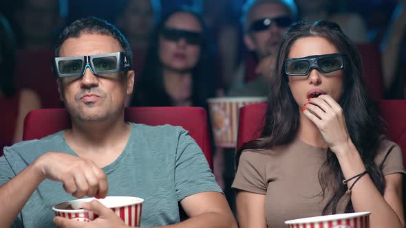 Closeup Focused Unbelievable Hispanic Couple Watching Interesting Film in 3D Glasses Eating Popcorn