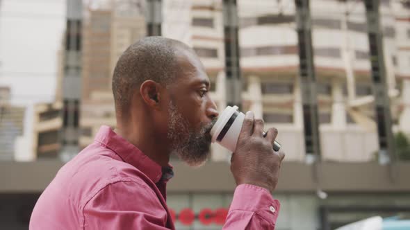 African American man drinking a coffee and using his phone