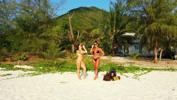 Modern smiling girls on holiday in the sun at the beach on paradise white sand and blue background 