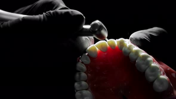 Close-up of a Dentist Practicing on a Mock-up of a Skeleton of Teeth Using a Drill Machine. the