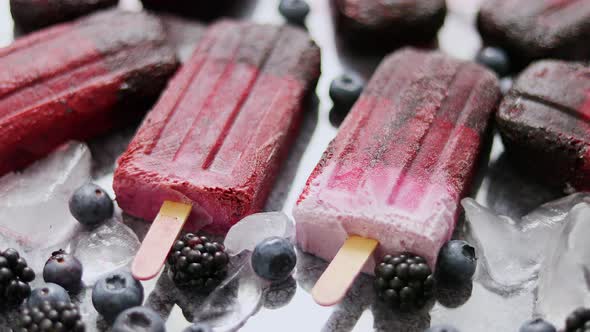 Homemade Blackberry and Cream Ice-creams or Popsicles with Frozen Berries on Black Slate Tray