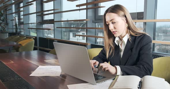 Concerned Woman Working on Laptop Computer and Looking Away Thinking Solving Problem at Office