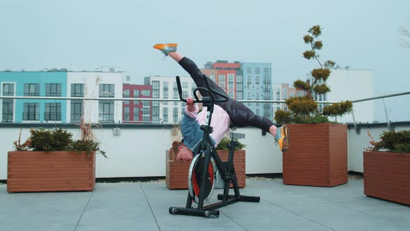 Athletic Woman Makes Twine Training Routine on Spinning Stationary Bike on House Roof Weight Loss