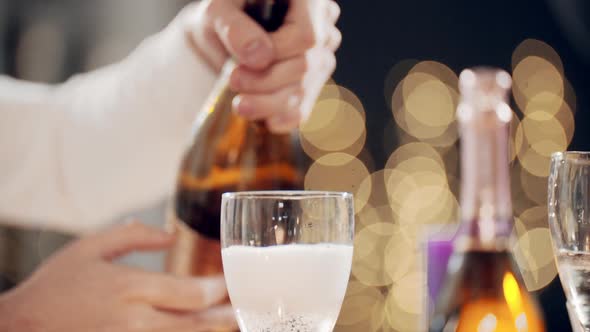 Closeup Shot of Hands Pouring Sparkling Wine From Bottle of Champagne Into Glasses with Foam