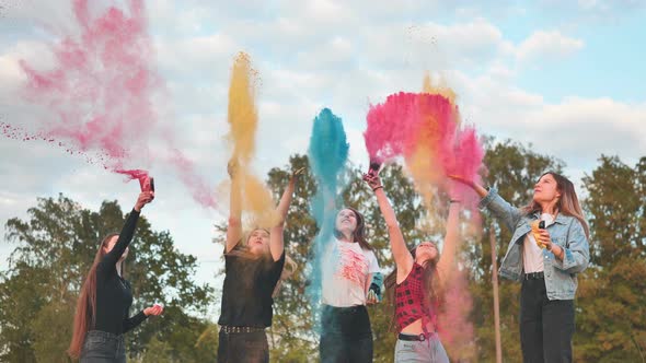 Cheerful Girls Toss Up Multicolored Powder