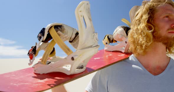 Blonde Man with Sand Board Looking at A Distance in Desert 4k