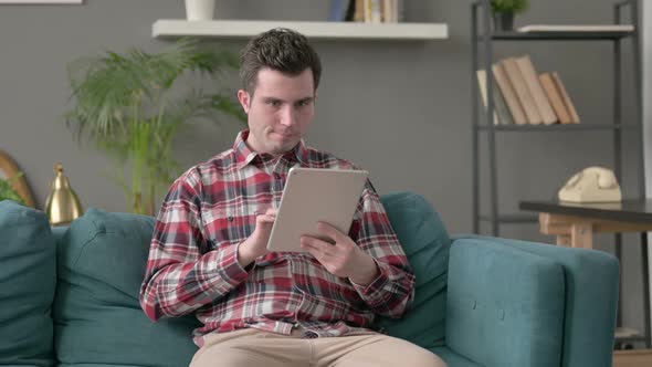 Man Having Loss on Tablet on Sofa