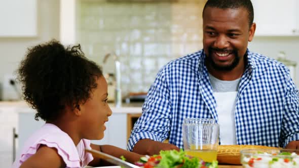 Father and daughter having meal on dinning table at home