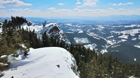 Aerial drone view of the spring Carpathians, Romania. Rocky peaks and valleys partly covered with sn