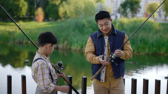 Asian Dad Shows His Son How to Fish Properly Gives Instructions About Fishing