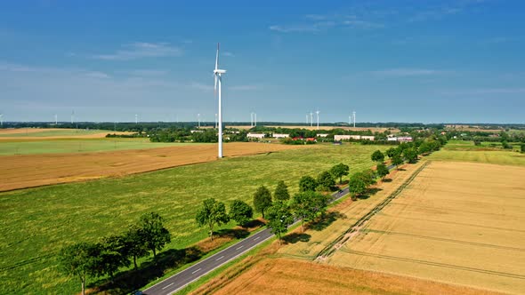 Wind turbines, road and golden fields in summer, aerial view