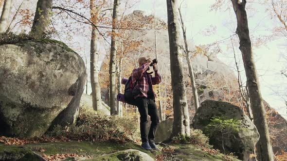 Young Bearded Man Photographing Cliffs High in the Mountains  Autumn Sunny Day