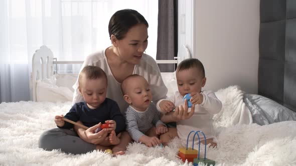 Happy Asian Mom Posing with Triplets and Smiling