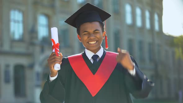 Happy Graduating Student Showing Success Gesture Holding Diploma, Education