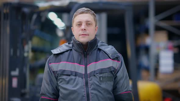 Medium Shot Portrait of Brunette Caucasian Adult Man in Uniform Standing in Warehouse Looking at