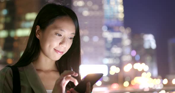 Woman sending message on cellphone in city at night