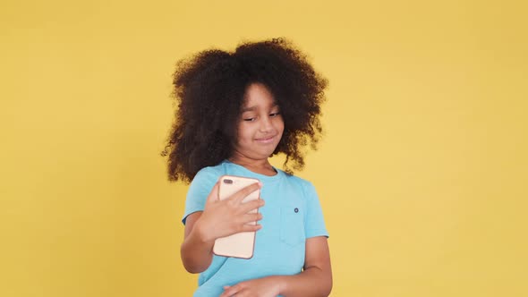 Small African American or Asian Little Cutie with Curly Hair. She Using Smartphone and Taking Selfie