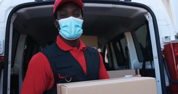 African man courier delivering packages with truck while wearing protective face mask