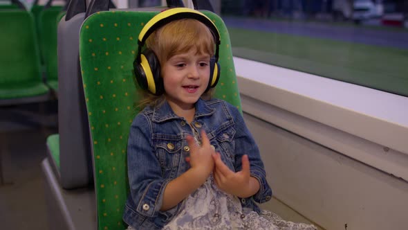 Lovely Child Girl Wearing Headphones Listening Music Relax Dancing While Traveling By Bus in City