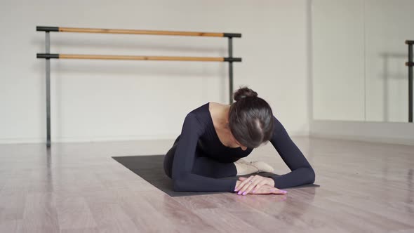 a Beautiful Dancer in Black Clothes Lies on a Mat in a Dance Class and Stretches Her Legs Before a