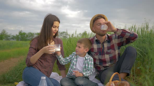 Nature Recreation, Happy Smiling Family with Child Boy Drink Milk During Picnic Outdoors in Green