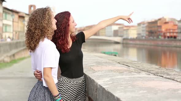 Two girls visiting a city and taking pictures with smart phone