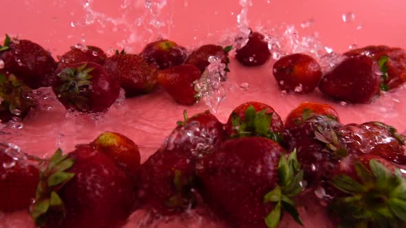 Splashes of water fall on strawberries. Slow motion.