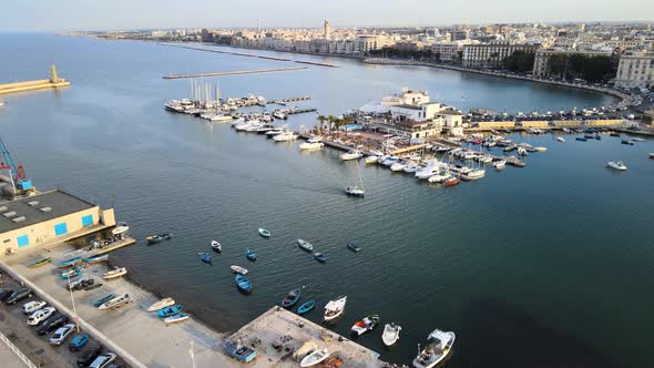 Aerial drone shot headed to the port of Bari, Italy. Lots of boats, yachts. During sunset. Small boa