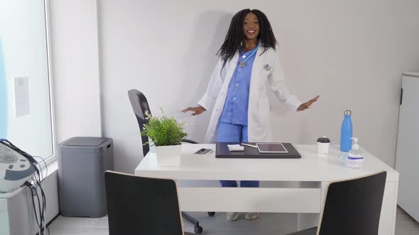 Black female doctor in medical uniform dancing in clinic