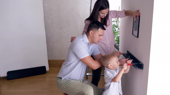 Repairs in Flat, Cute Child Boy Helps Parents To Bolt Shelf To Wall After Relocation in Apartment