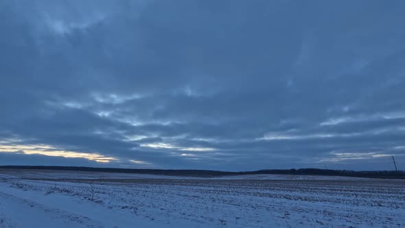 Timelapse, clouds in the sky in winter over a field covered with snow.