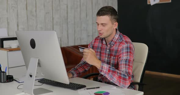 Man Makes Purchases Over the Internet on a Computer and Pays By Credit Card at the Office