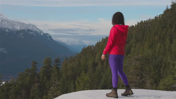 Adventurous Girl Hiking in the Mountains During a Sunny Winter Sunset