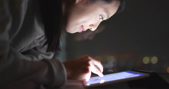Woman working on tablet computer at night