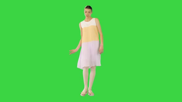 Young Beautiful Girl in Whiteyellow Dress Walks Waving Arm on a Green Screen Chroma Key
