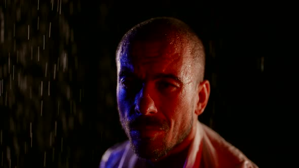 Closeup of a Male Face in the Dark in the Streams of Water