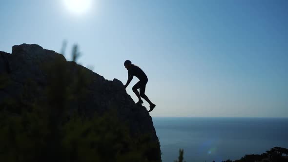 Young Long-haired Inspired Man Raises His Hands Up Standing on the Top of a Mountain Above the Sea